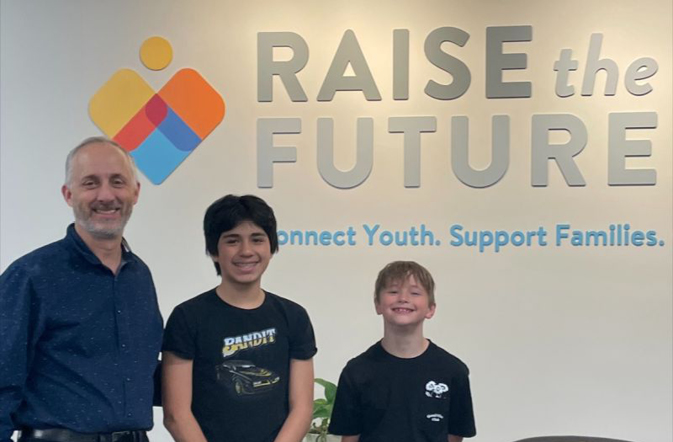 Marc Hendrikson from Sunflower Bank with two boys in front of Raise the Future signage