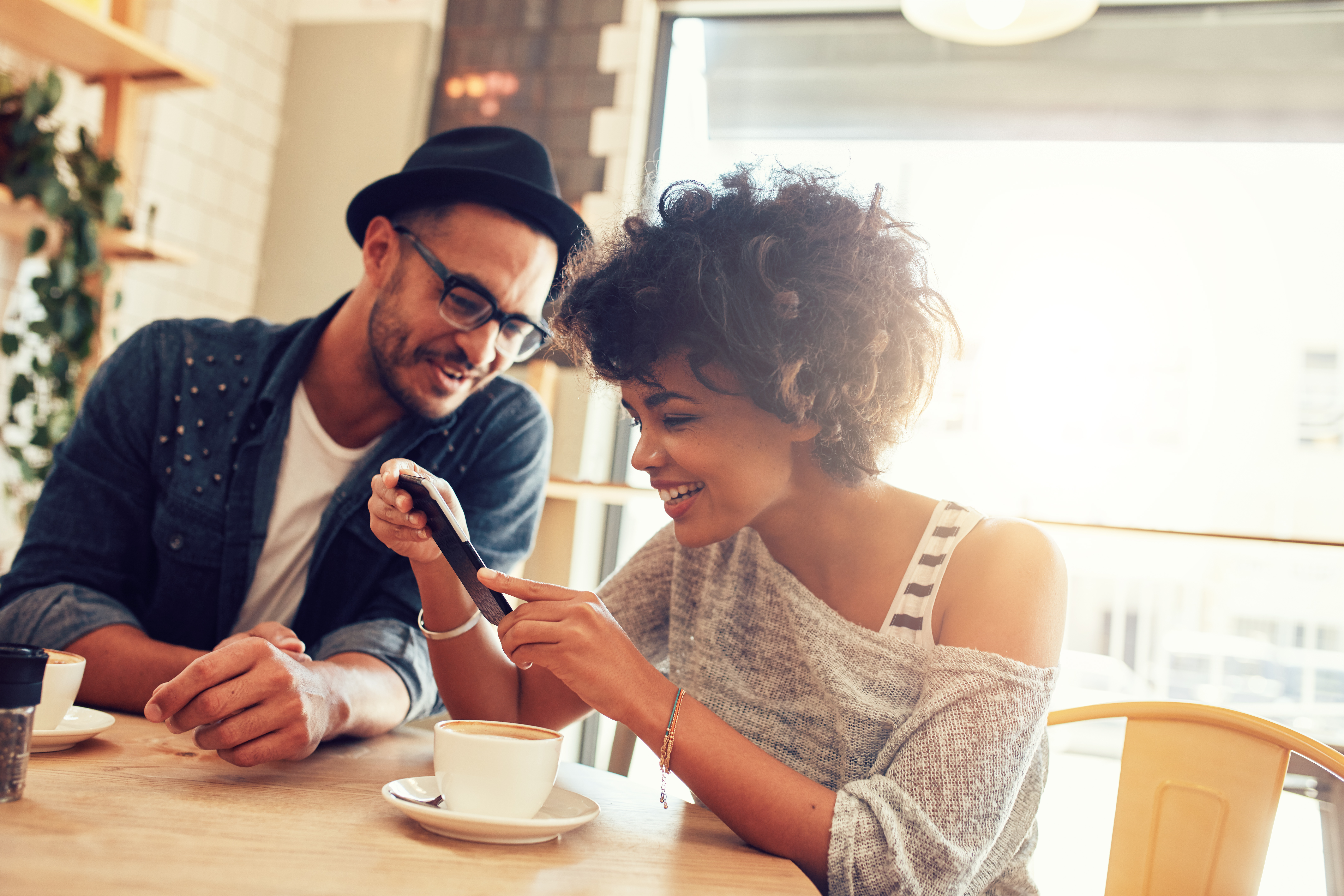 two people looking at a phone over coffee