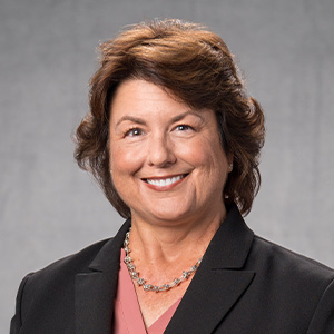 Headshot of Elise Giles in black jacket gray background