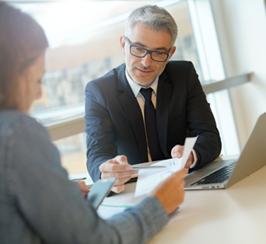 man with suit talking to woman holding a paper