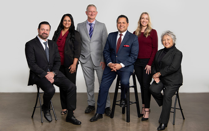 professional photo of six employees standing and sitting on stools
