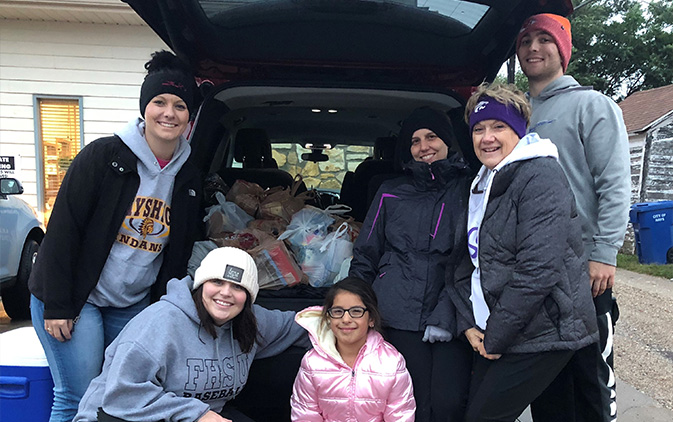 group of people by open car truck with donations
