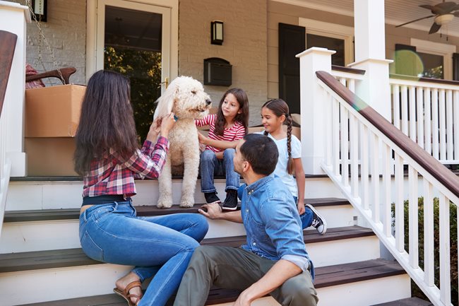 family with dog on front porch with moving boxes