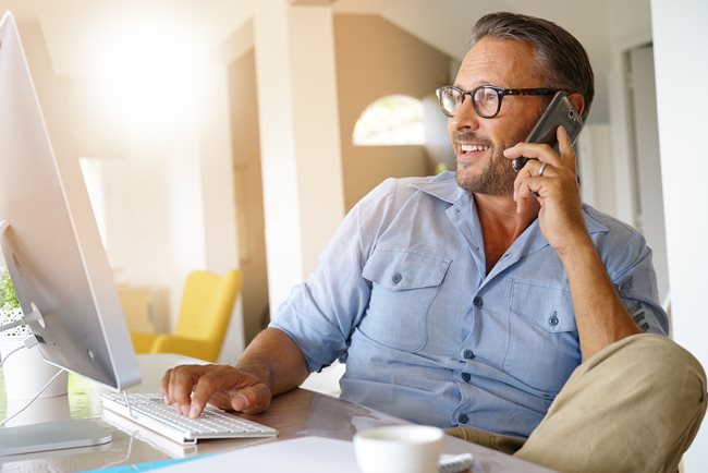 man smiling on the phone looking at monitor