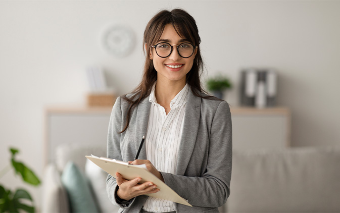 women in business attire at house with clipboard smiling