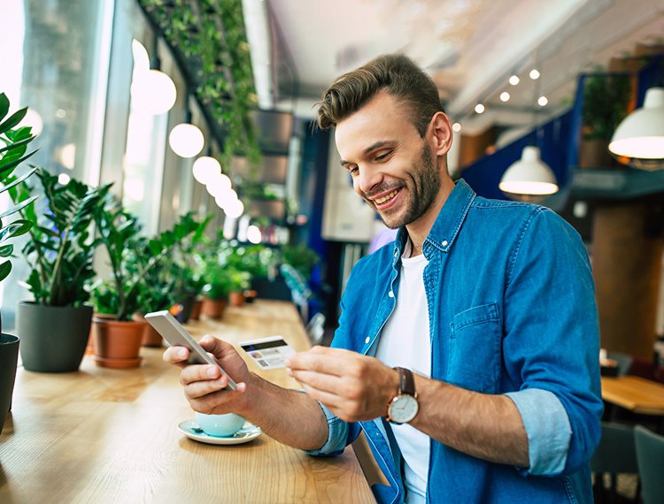 Male customer at a coffee shop utilizing Sunflower Bank's online banking