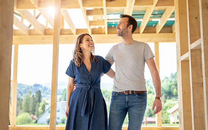 couple walking through wood house framing