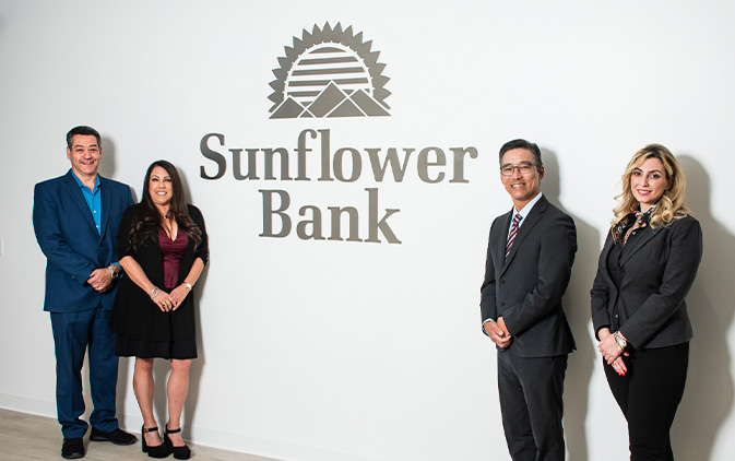 four team members in front of Sunflower Bank sign