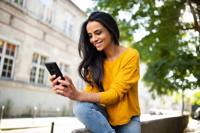 happy woman with yellow shirt looking at phone