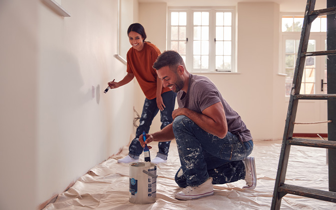 couple painting wall in new house