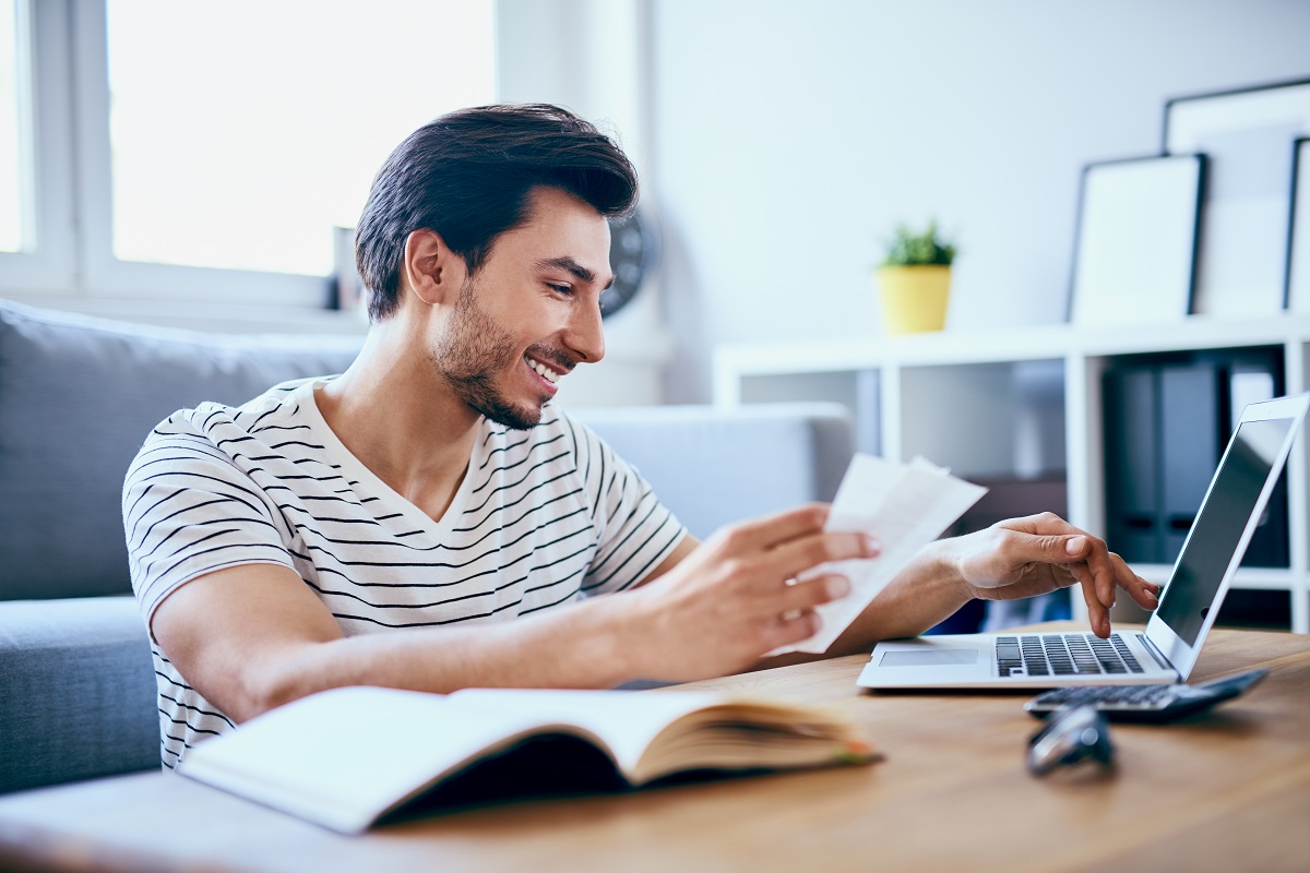man smiling while typing on laptop